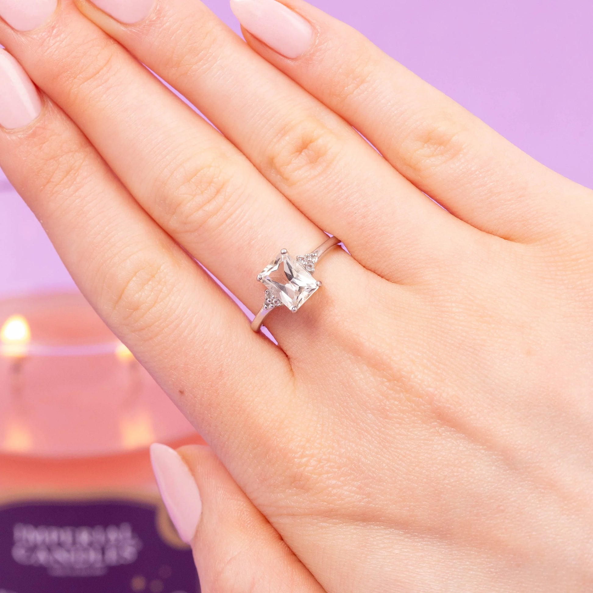 Sparkling ring on hand with Imperial Candles Brazilian Beauty candle in background, showcasing luxurious fragrance layers.