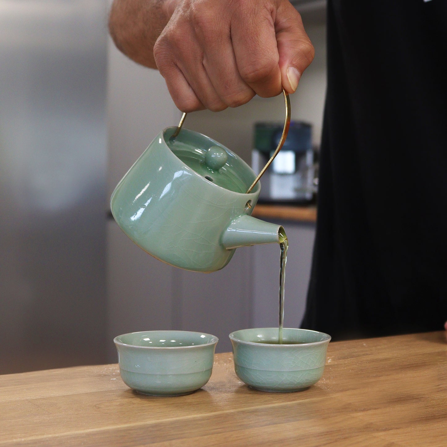 Elegant Herbal Jade Teapot Set - Pot pouring tea into two matching cups, perfect for serene tea moments.