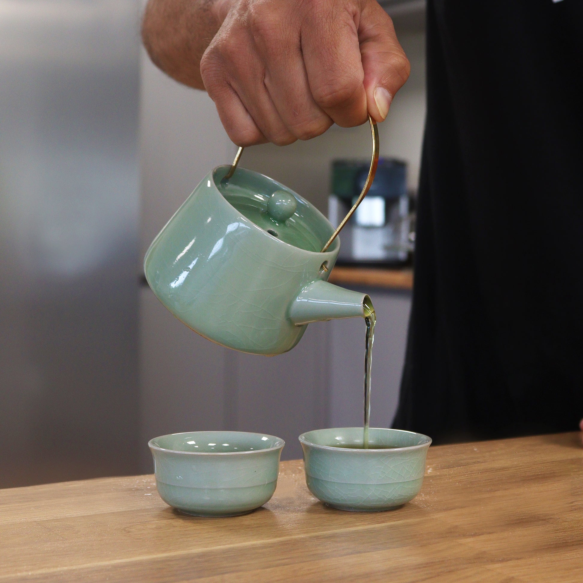 Elegant Herbal Jade Teapot Set - Pot pouring tea into two matching cups, perfect for serene tea moments.