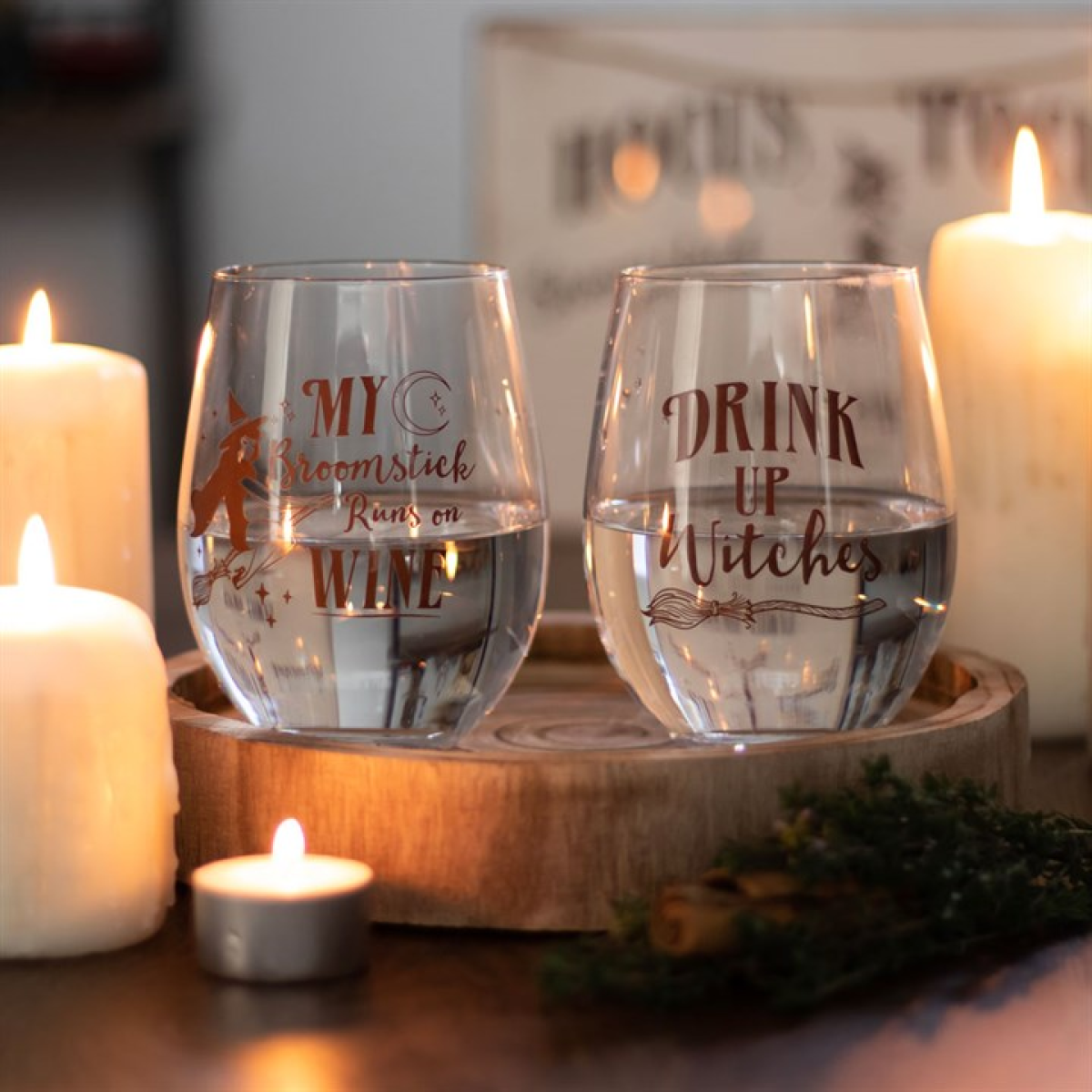 Stemless wine glasses with witchy quotes: 'My broomstick runs on wine' and 'Drink up witches' on a wooden tray.