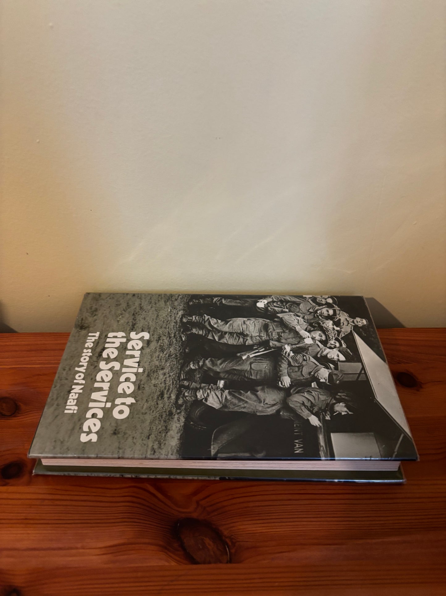 Hardcover book titled "Service to the services: The story of Naafi Hardcover – 1 Jan. 1971" on a wooden surface.