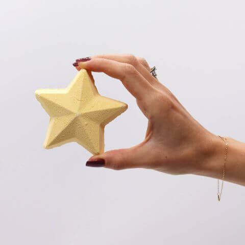Hand holding a star-shaped bath bomb from the Follow the Star Christmas Bath Bomb Gift Pack, perfect for festive relaxation.