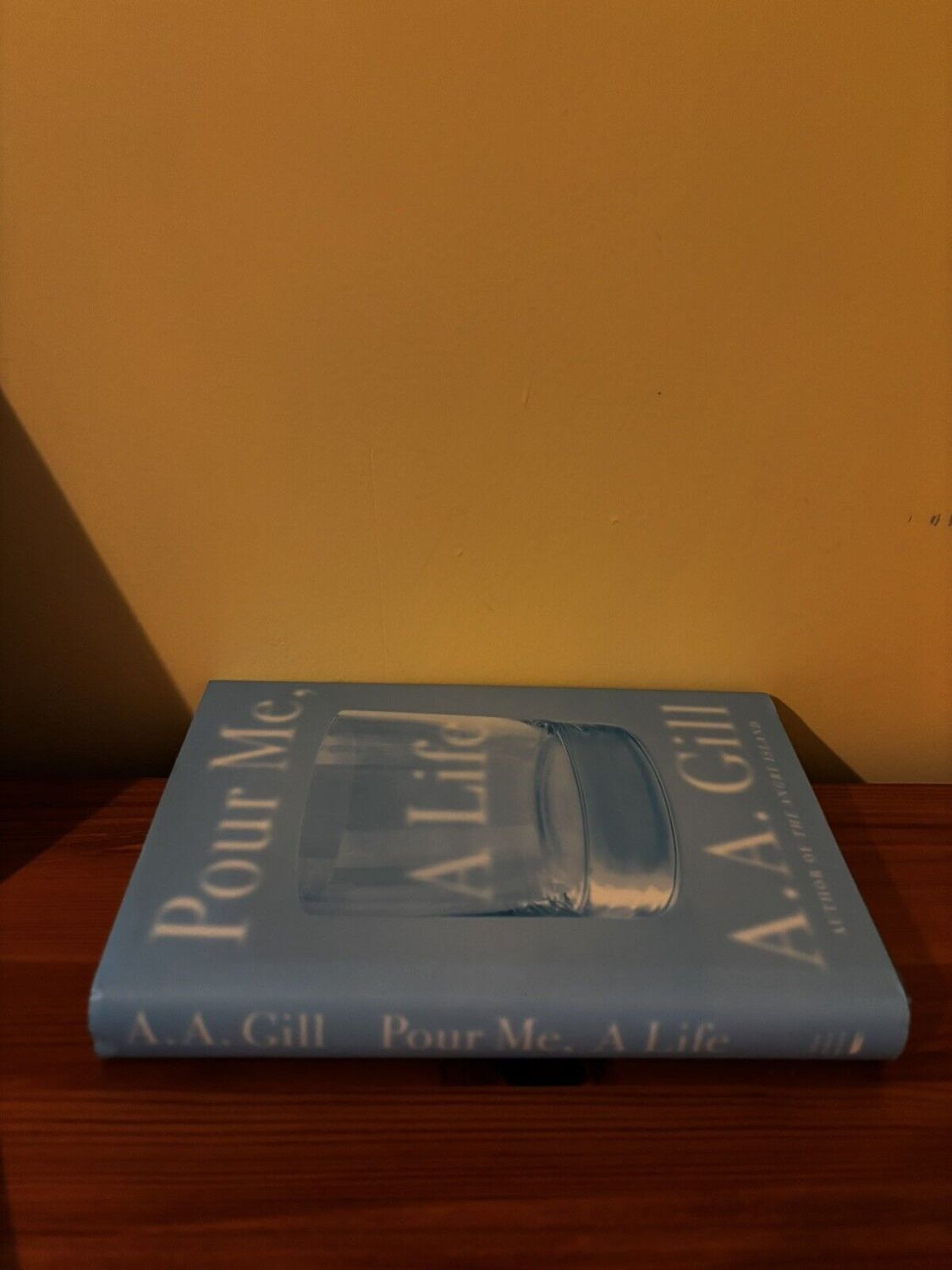 Cover of "Pour Me, a Life by Gill, A.A" on a wooden surface, showcasing its powerful memoir on addiction and recovery.