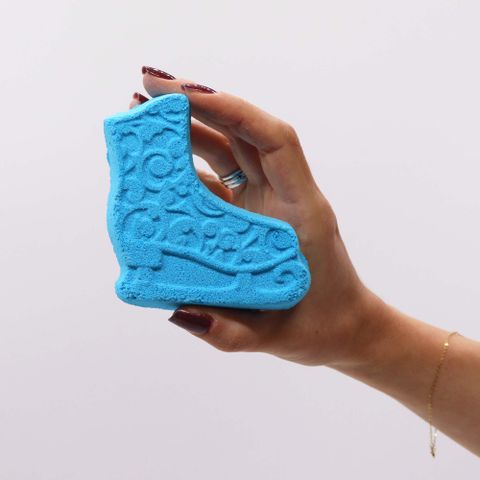 Hand holding a blue boot-shaped bath bomb from the Christmas Fun Bath Bomb Gift Pack for festive relaxation.
