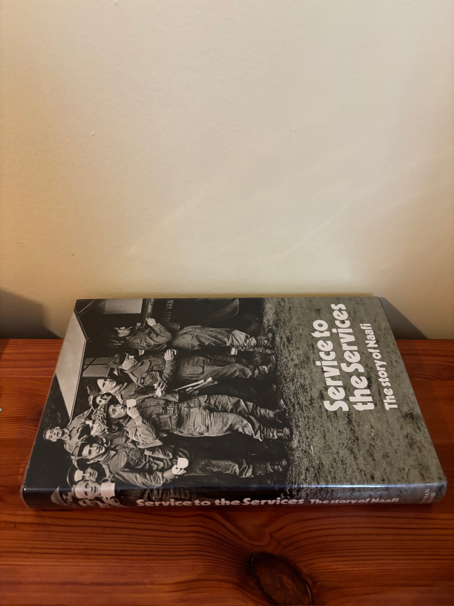 Hardcover edition of "Service to the services: The story of Naafi Hardcover – 1 Jan. 1971" displayed on a wooden table.