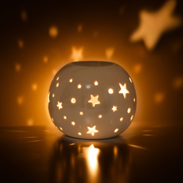 White Iridescent Star Oil Burner and Wax Warmer with star cut-outs casting a warm glow.