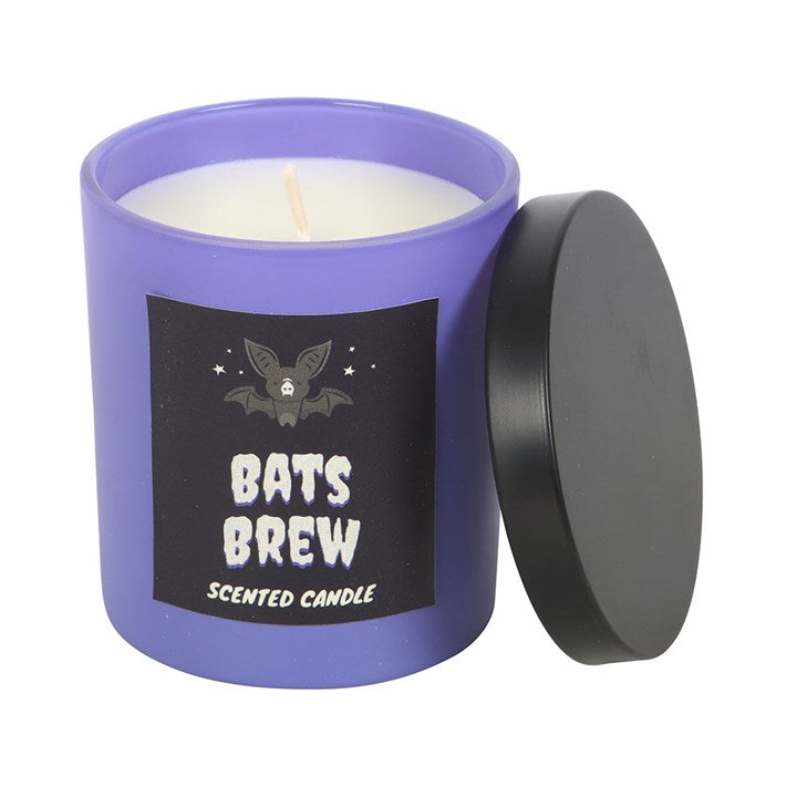 Bat's Brew Clove and Tobacco Candle in a purple jar with a black label and the lid resting beside.