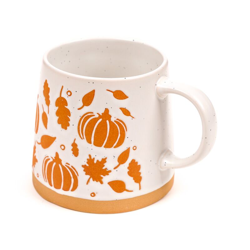 Stoneware mug with orange pumpkin and leaf motifs on white speckled glaze, orange base.