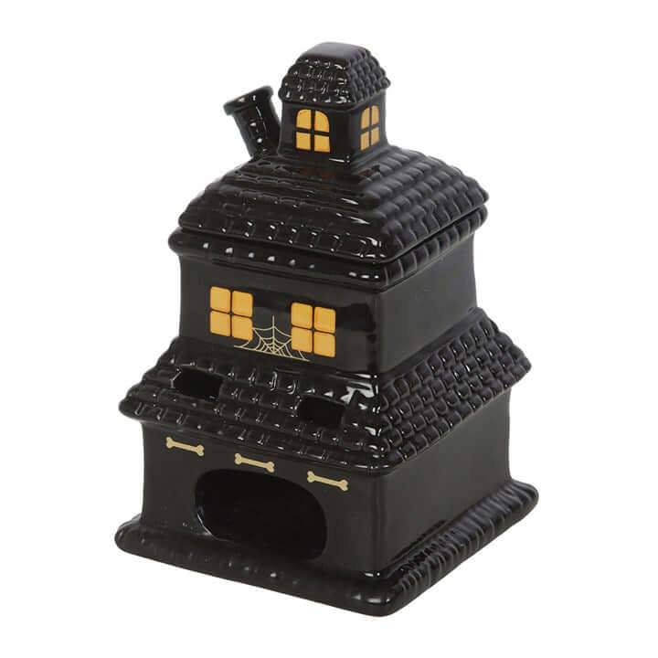 Black haunted house oil burner and wax warmer with warm yellow-lit windows and spooky multi-roof design.