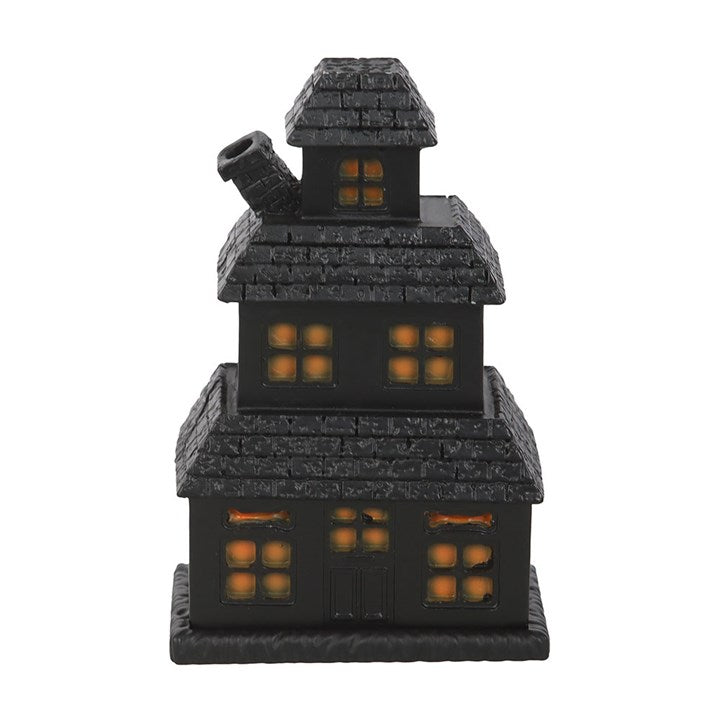 Black haunted house incense cone holder with glowing orange windows and chimney smoke.