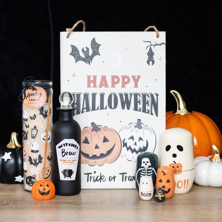 Spooky Spiced Pumpkin Black Cat Tube Candle among Halloween pumpkins and a Happy Halloween sign.