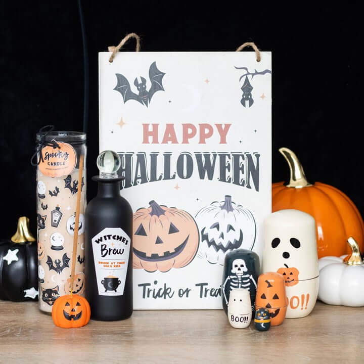 Spooky Spiced Pumpkin Black Cat Tube Candle among Halloween pumpkins and a Happy Halloween sign.