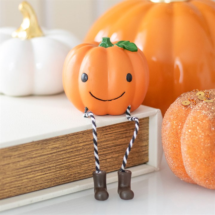 Cute Smiling Pumpkin Shelf Sitter Ornament with dangly legs, adding playful charm to Halloween decor at your home.