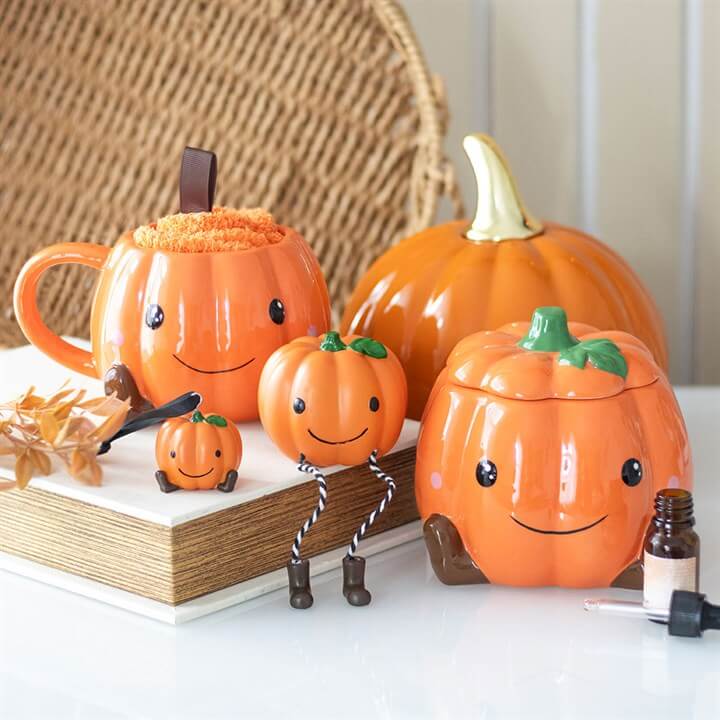 Cute smiling pumpkin mug set with cosy Halloween decor and tiny pumpkin figures.