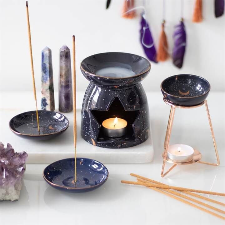 Purple star-sign oil burner on gold-coloured metal base with constellation bowl and lit candle.