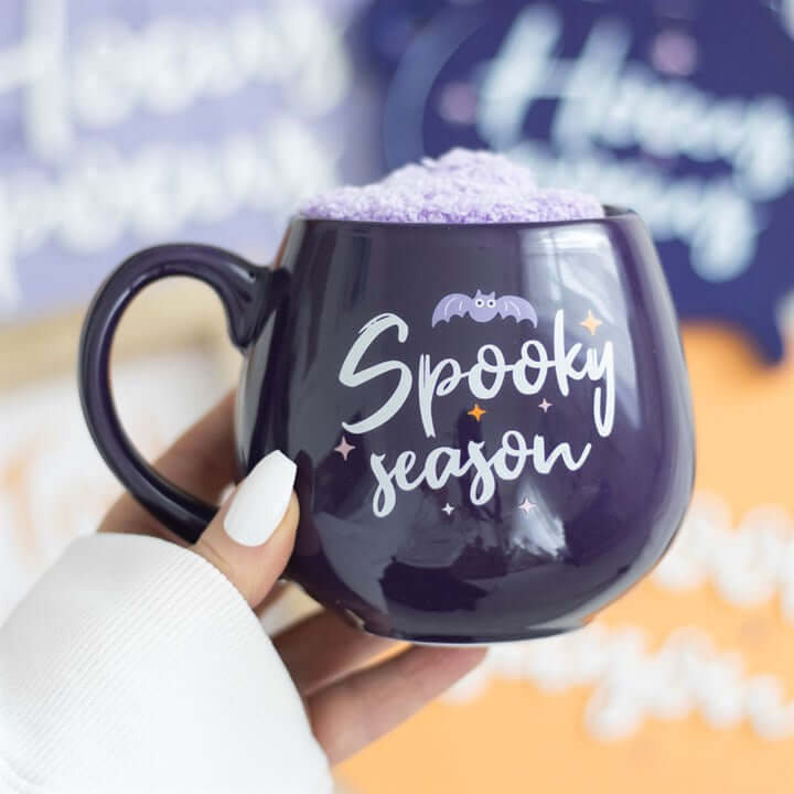 Delight in the Spooky Season Mug and Socks Set, featuring a charming purple mug and fluffy lilac socks for cosy autumn nights.
