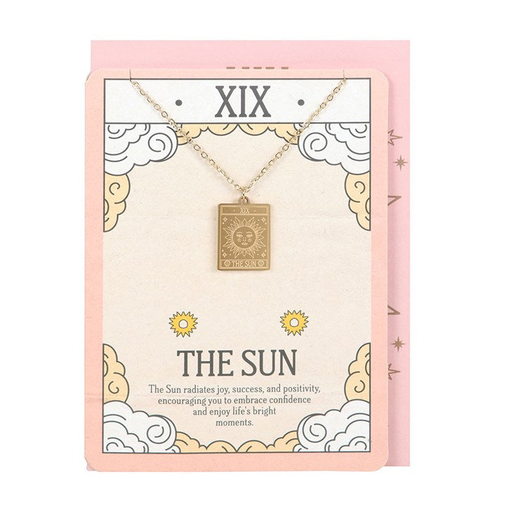 Gold-toned The Sun vintage tarot card pendant necklace on an illustrated greeting card.