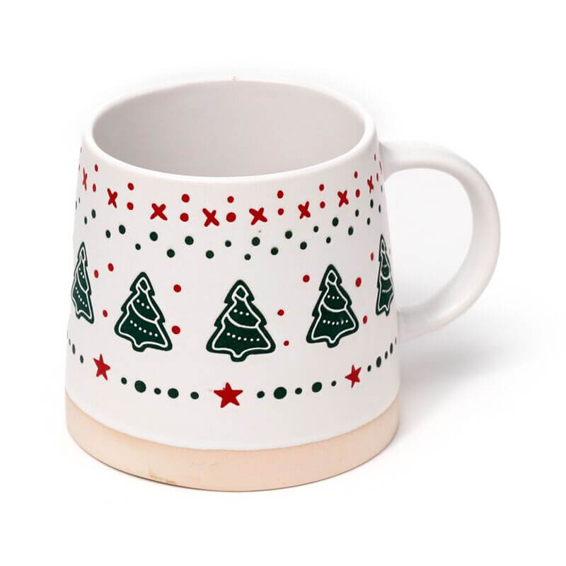 Stoneware mug with Christmas tree motif in green, red stars and dots on white, with a beige base.