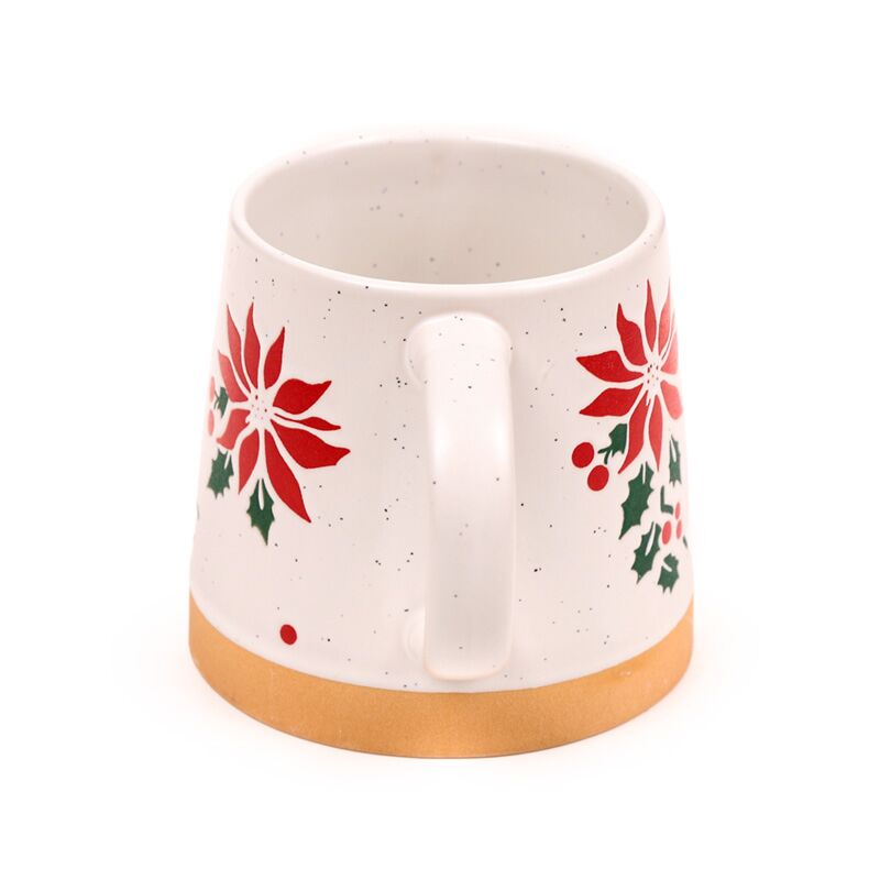 Stoneware mug with white speckled glaze, red poinsettia pattern, green holly leaves and a gold base.