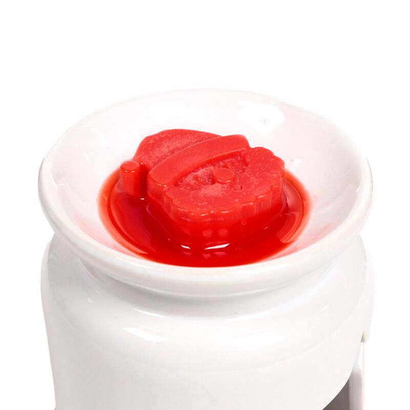 Red Christmas wax melt in a white ceramic warmer dish.