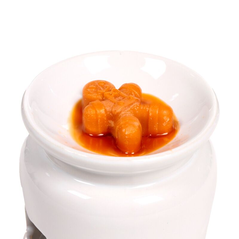 Cosy Christmas Jingle Bunch wax melts in orange, melting in a white ceramic warmer.