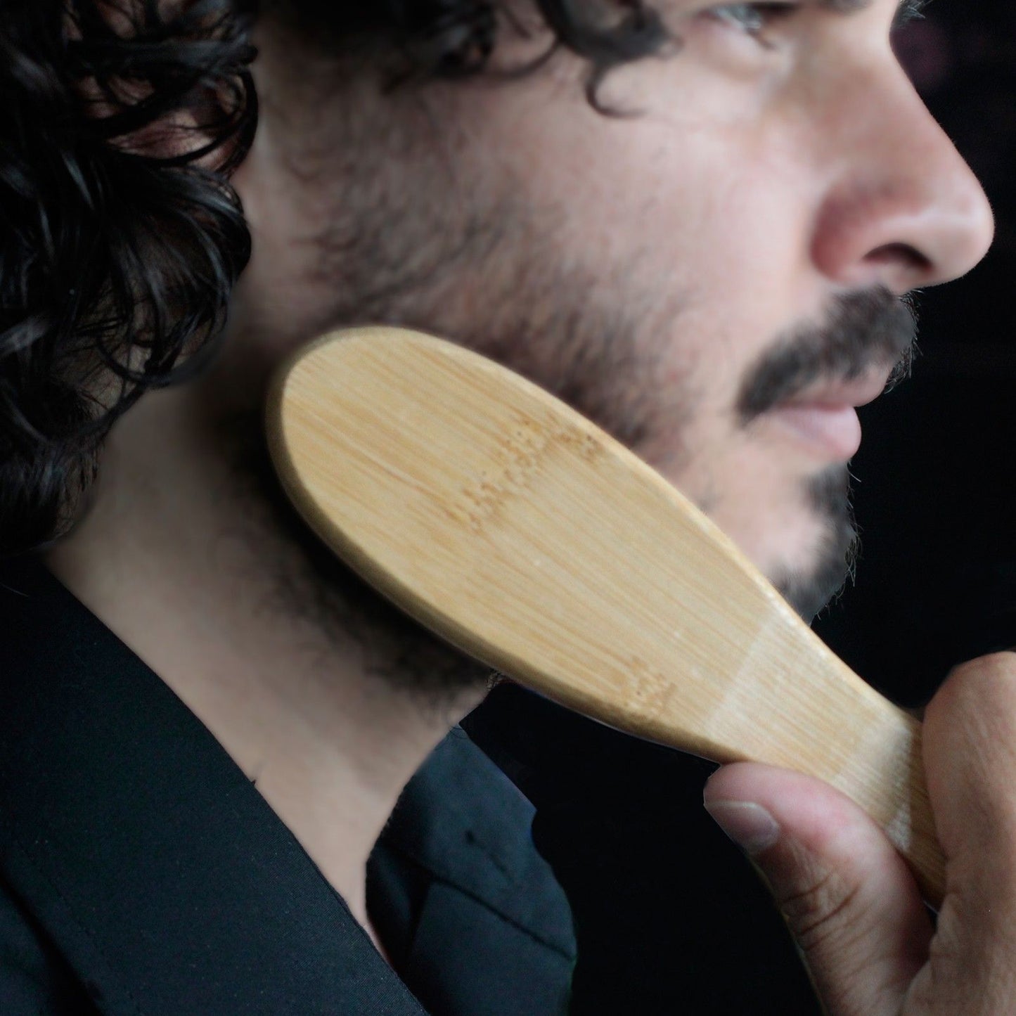 Beard brush with bamboo handle and boar hair bristles used on a beard.