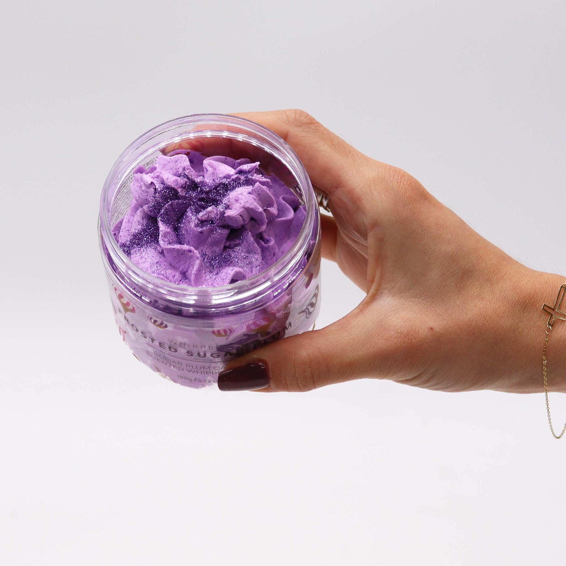 Purple Frosted Sugar Plum whipped soap in a 120g clear jar, held in a hand.