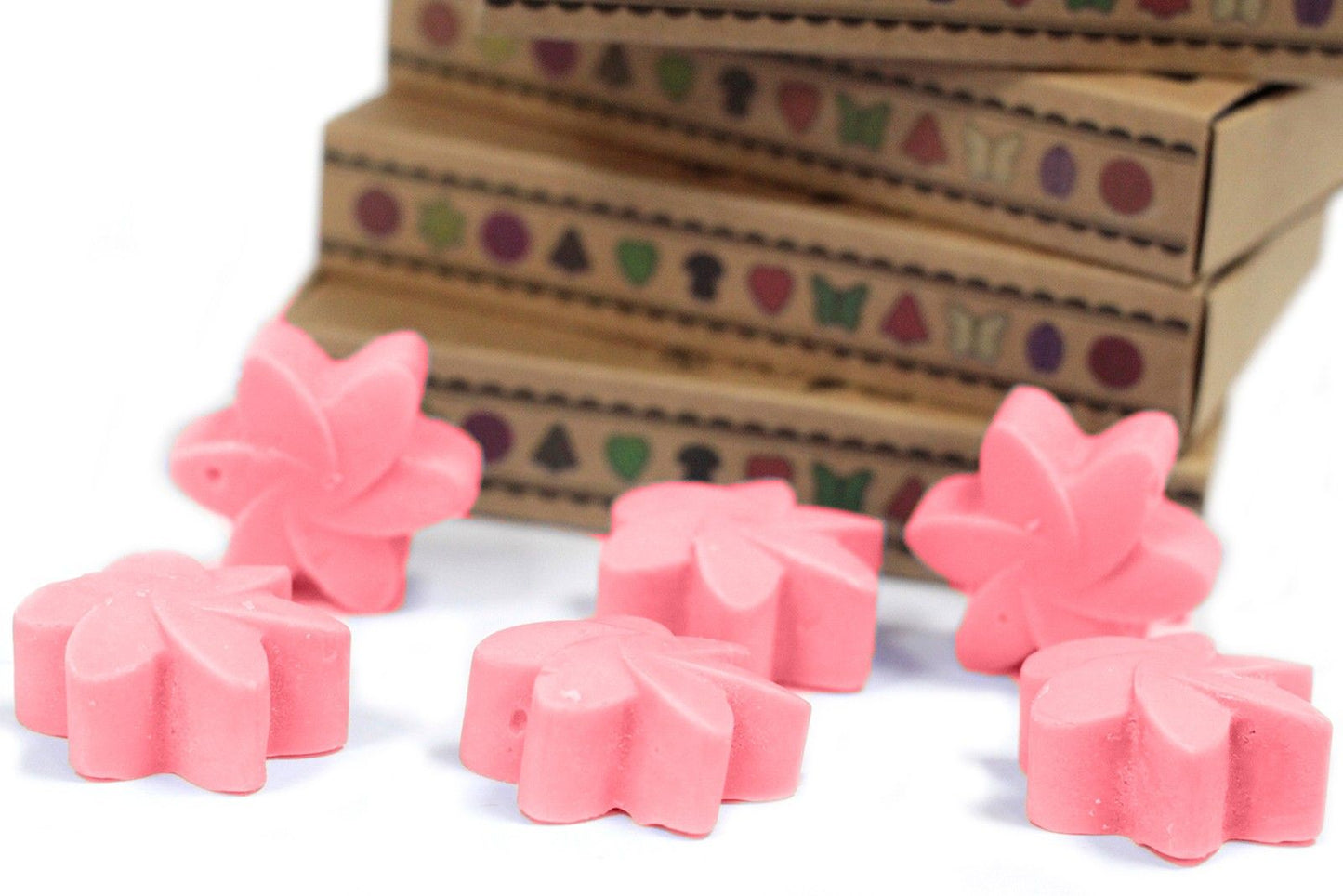 Six pink Japanese Magnolia wax melts in flower shapes, with matchbox-style packaging in the background.