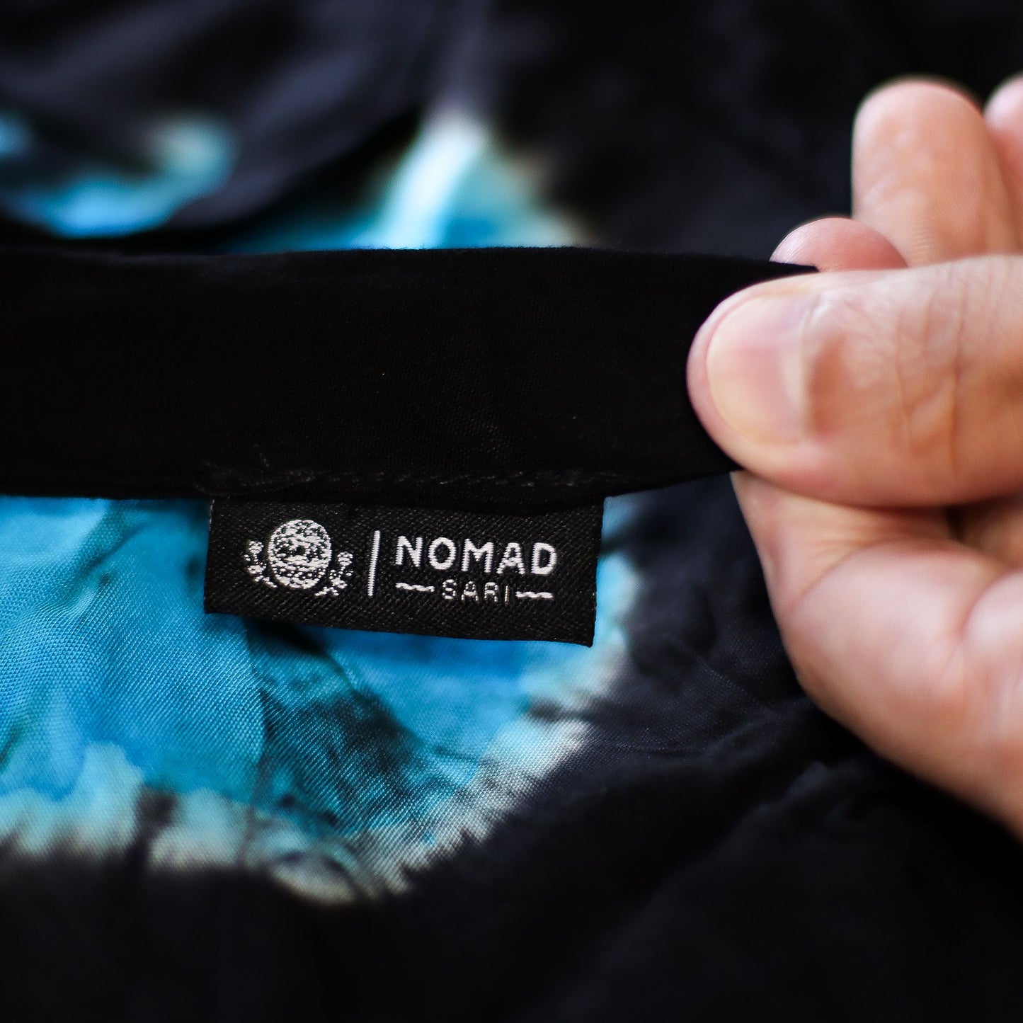 NOMAD SARI tag on black waistband of Japanese-style tie-dye lounge pants in blue and black.