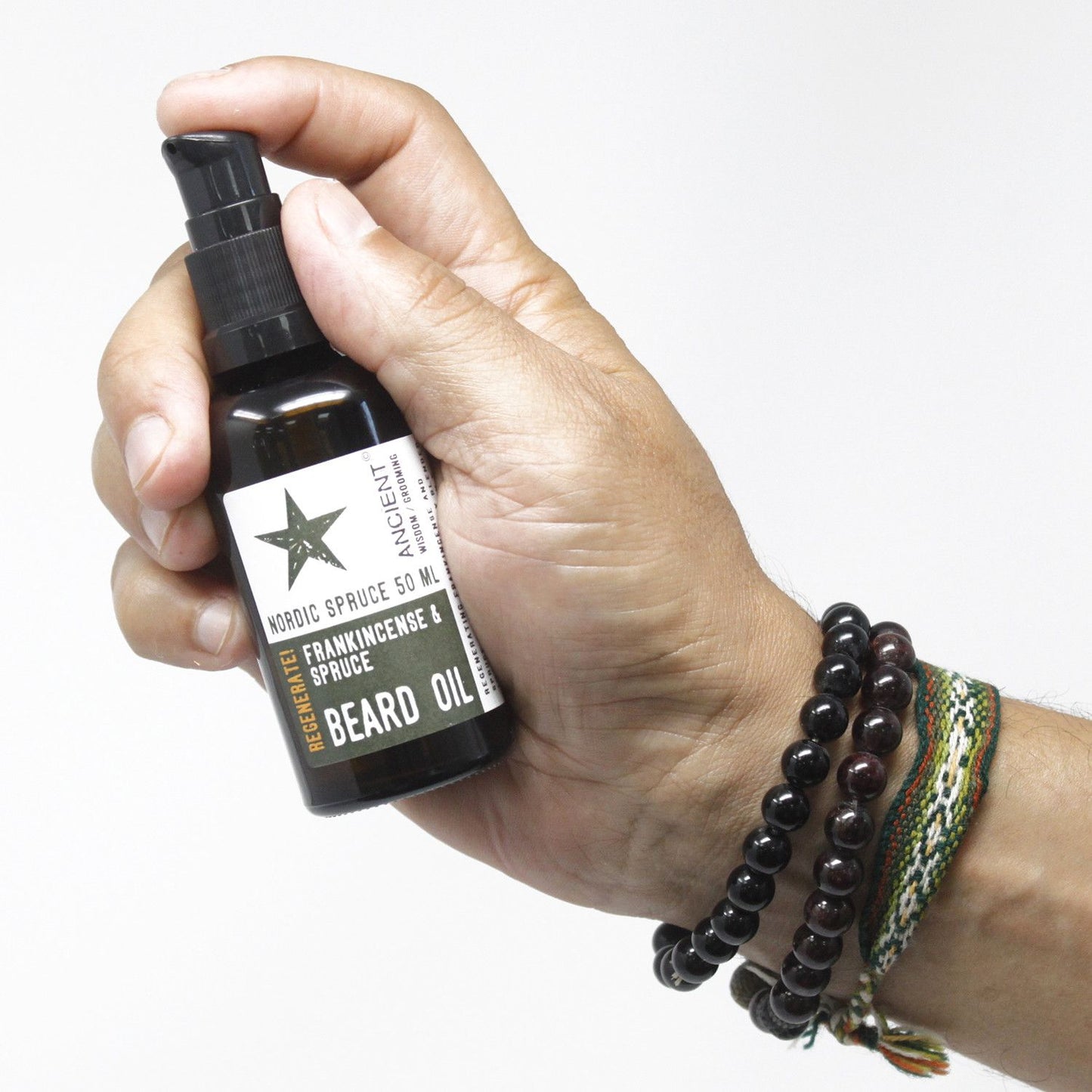 Hand holding 50ml Nordic Spruce Beard Oil bottle for beard care and skin regeneration; frankincense and spruce scent.