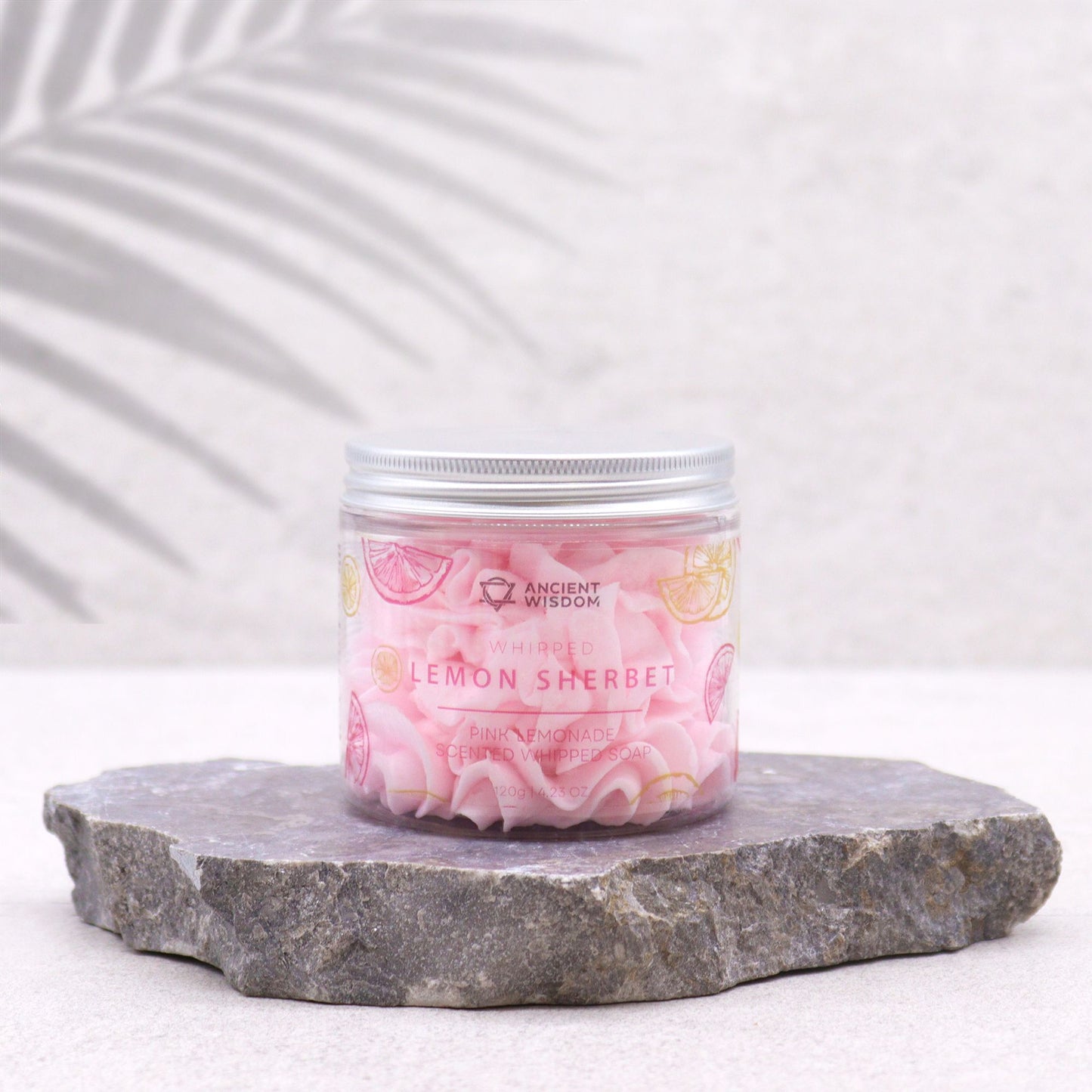 Ancient Wisdom Pink Lemonade Scented Whipped Soap 120g in clear jar with lemon sherbet label on a stone slab
