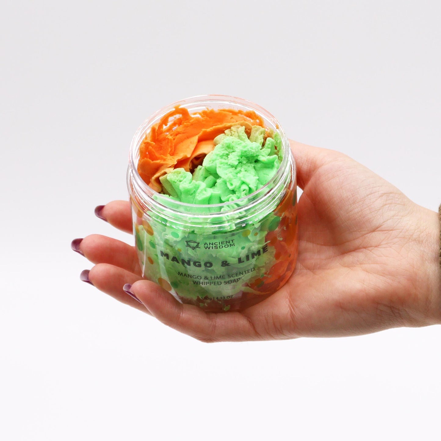 Mango & Lime Whipped Soap 120g in a clear jar with green and orange swirls, held in a hand.