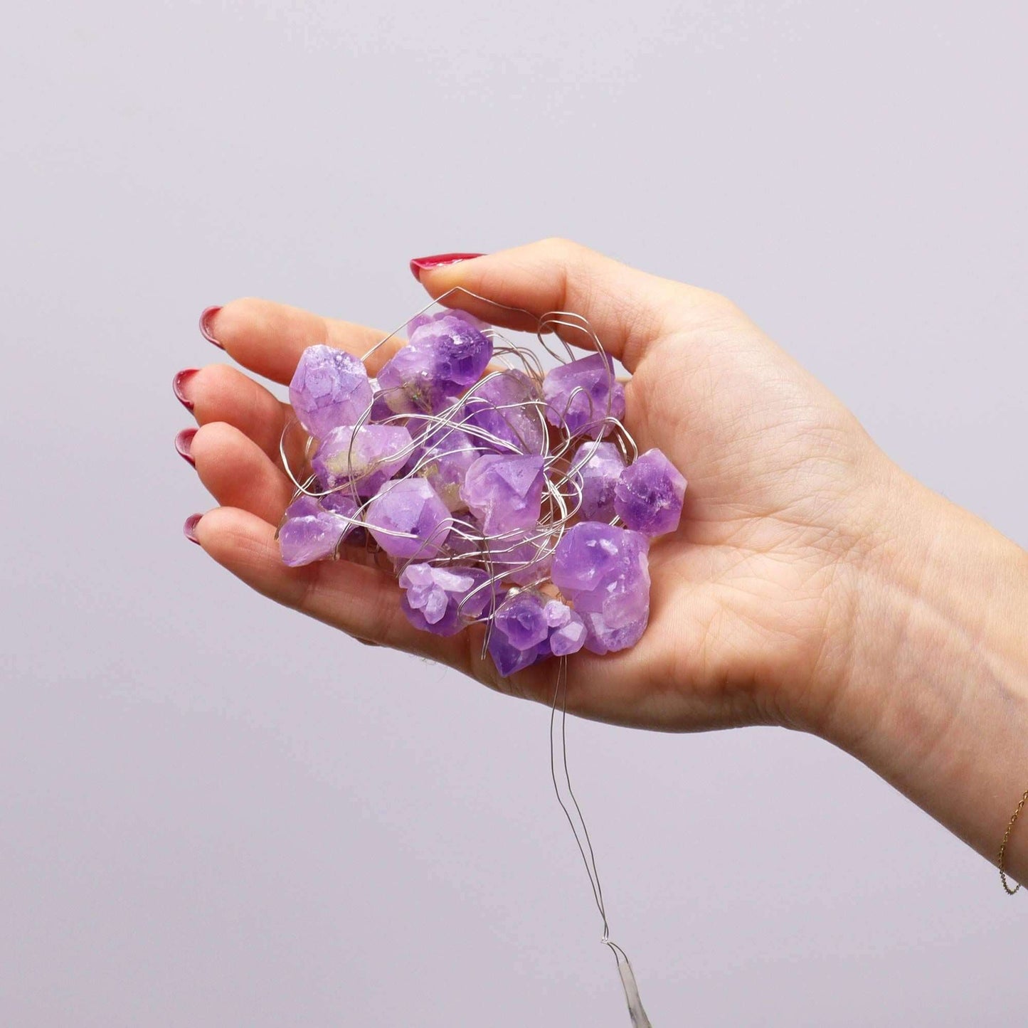 Amethyst Gemstone Enchantment Lights USB String held in hand with glowing purple crystals.