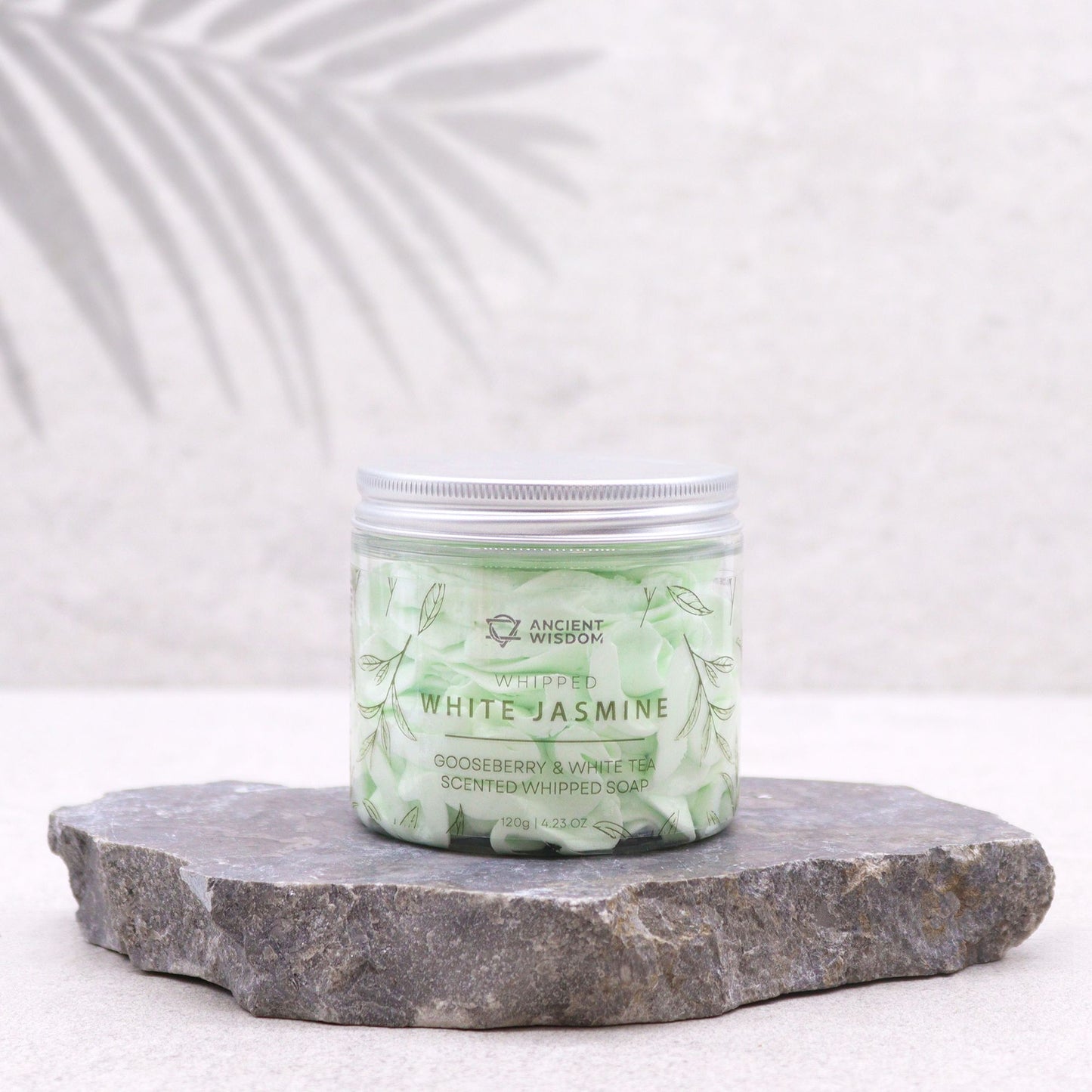 Gooseberry and White Tea scented whipped soap in a green jar labelled White Jasmine on a stone slab.