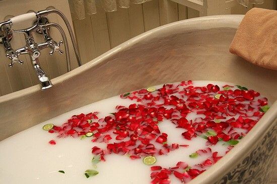 Luxurious bathtub filled with rose petals and lime slices for a relaxing soak experience.
