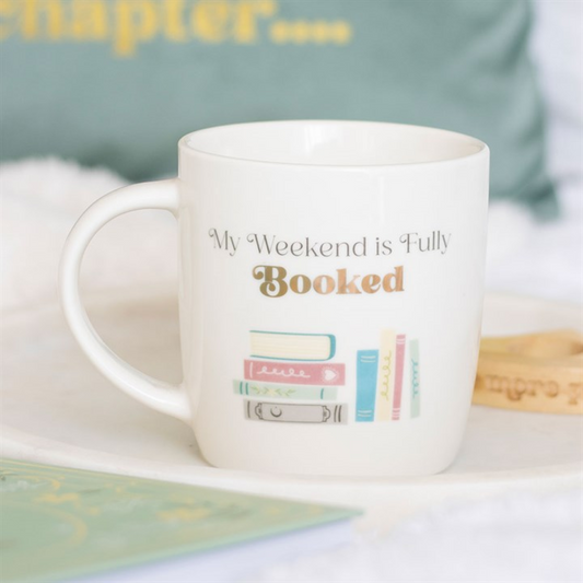 My Weekend is Fully Booked mug on white ceramic with a colourful stack of books.