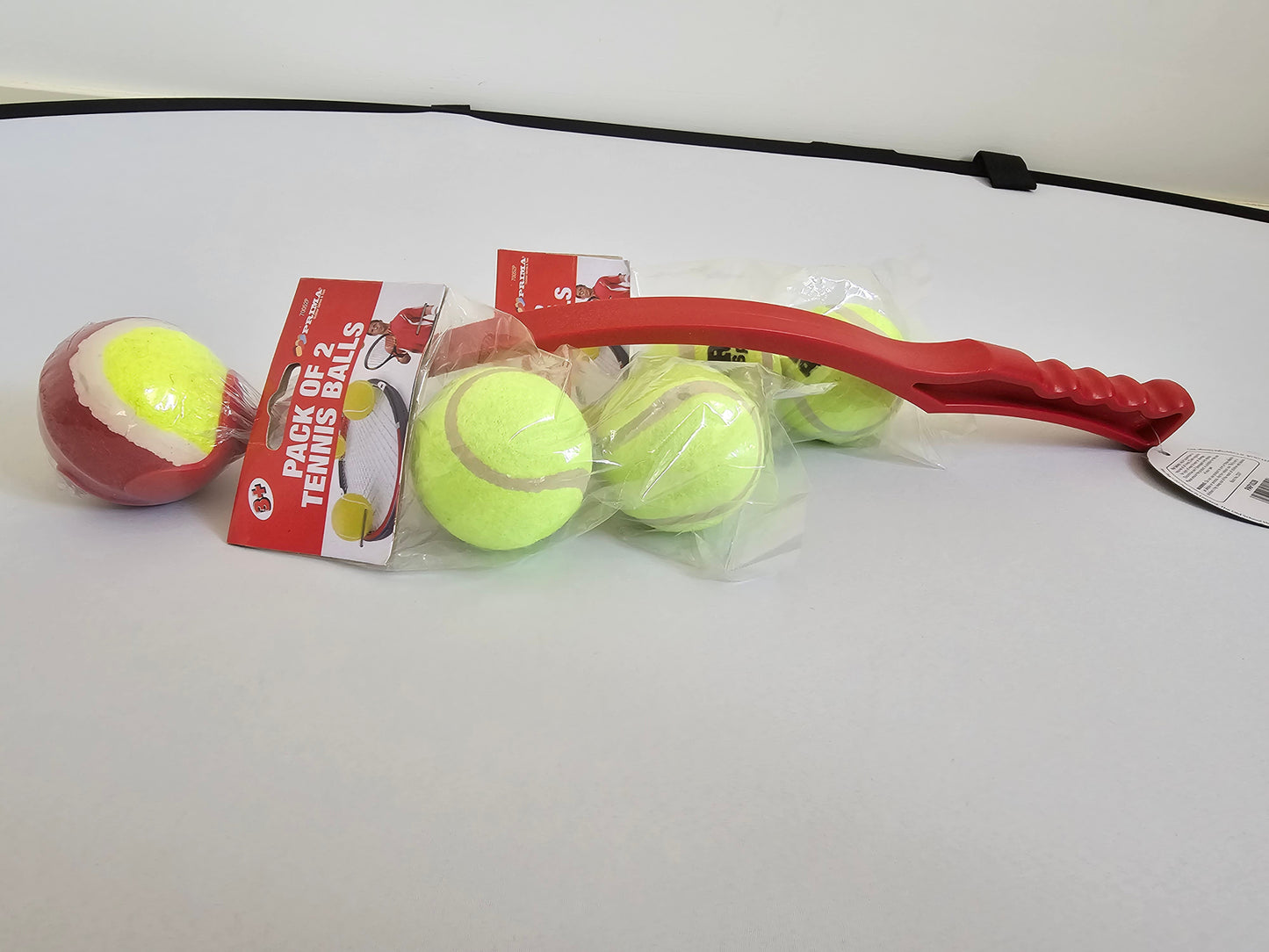 Tennis ball launcher and refill pack with bright yellow balls and red handle for extended dog fetch sessions