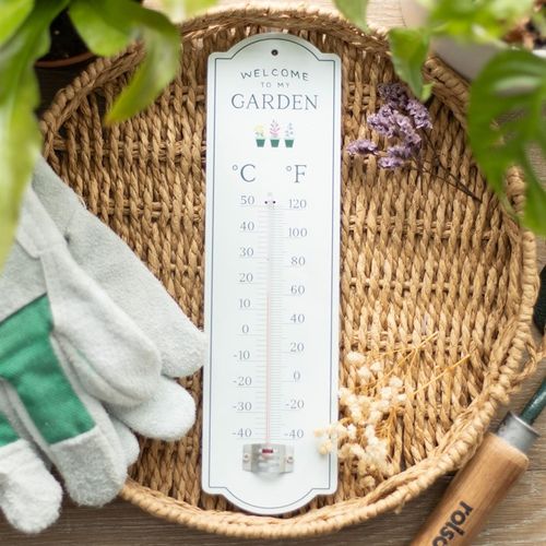 Welcome to My Garden Wall Thermometer displayed on a woven tray, perfect for monitoring garden temperatures.