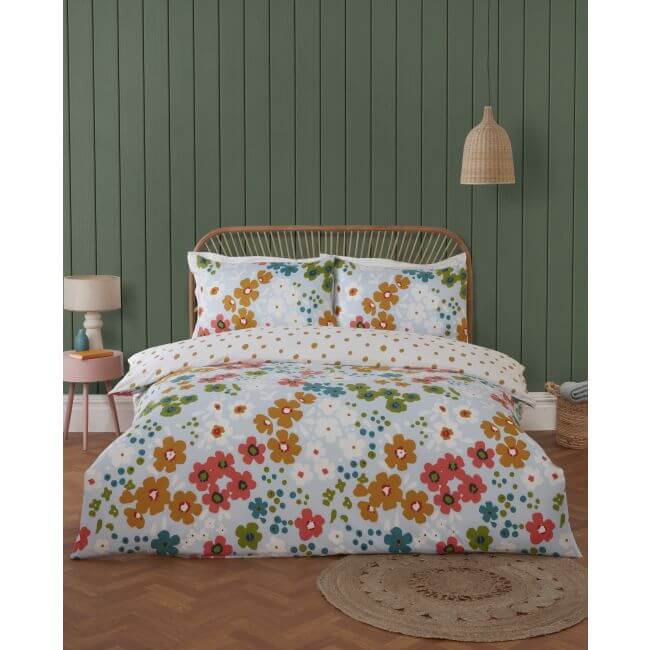 Floral duvet cover set on a bed with a green paneled wall and wooden floor.