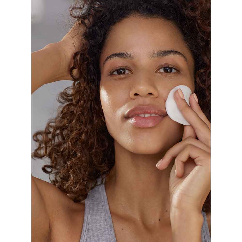 Woman applying Avon Nutra Effects Nourish Oil-Infused Micellar Water on her face for a refreshing cleanse.