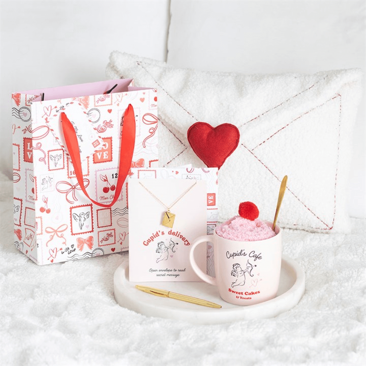 Valentine postage stamp gift bag with a necklace card, heart décor, and dessert on a cozy surface.