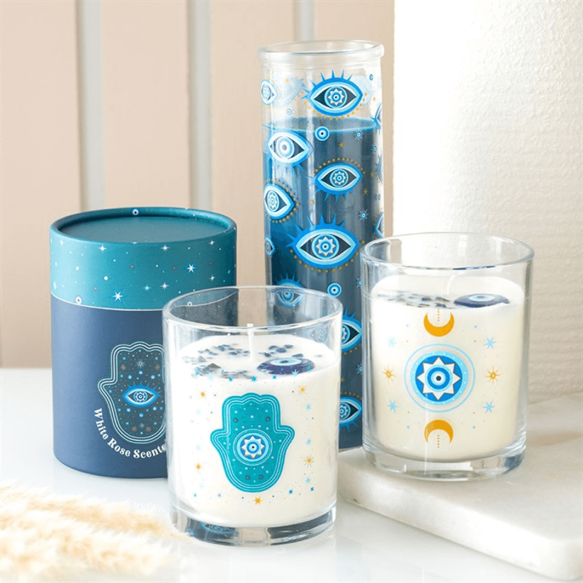 Under Watchful Eyes White Rose Candle With Crystals in decorative turquoise glass containers with all-seeing eye designs.