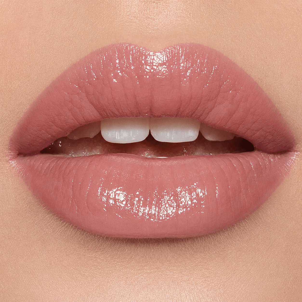 Close-up of glossy nude pink lips on a model's mouth, showing a high-shine lip color with a soft rosy pink tone.