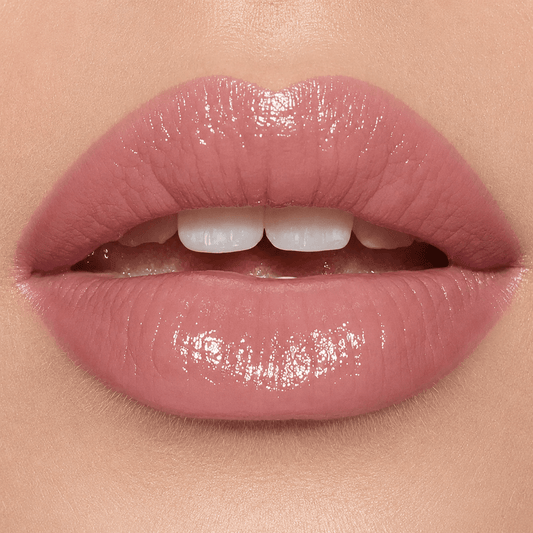 Close-up of glossy nude pink lips on a model's mouth, showing a high-shine lip color with a soft rosy pink tone.