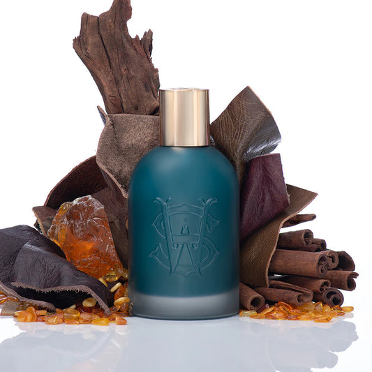 Saltworks Eclipse fragrance bottle with teal frosted glass and gold cap, surrounded by cinnamon sticks and amber.