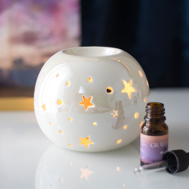 White Iridescent Star Oil Burner and Wax Warmer — celestial white ceramic with star cut-outs and warm glow.