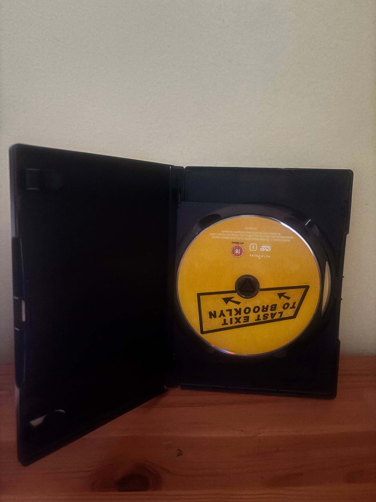 DVD case with a yellow disc featuring a logo on a white surface.