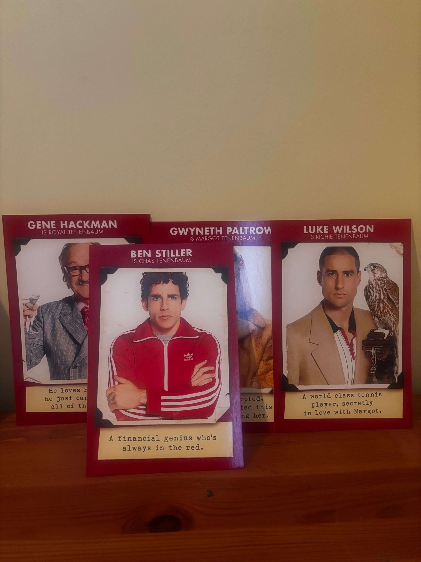 Three trading cards featuring different individuals on a wooden surface.