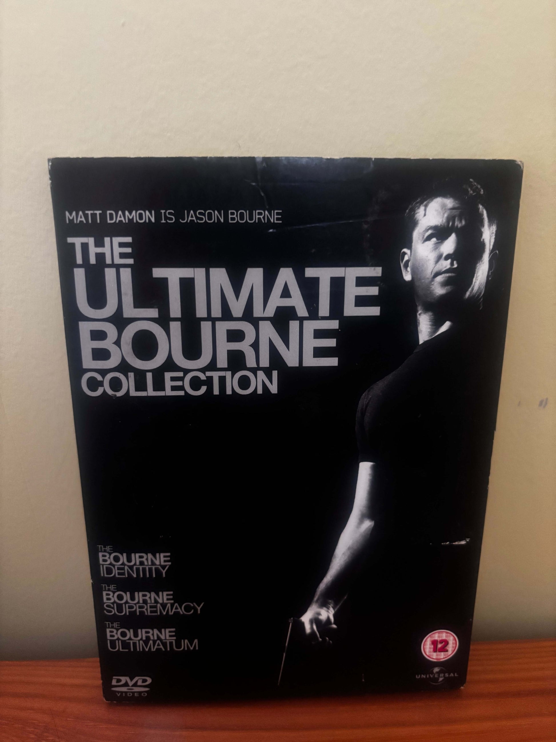 DVD box set titled 'The Ultimate Bourne Collection' on a beige surface.