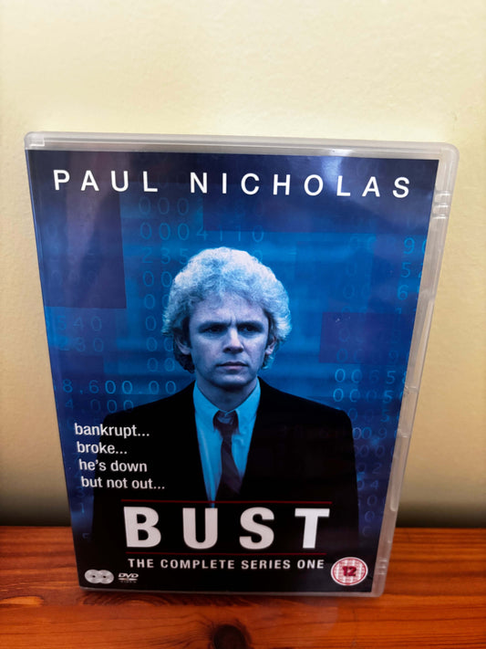 DVD case for 'Bust' with Paul Nicholas on a wooden surface